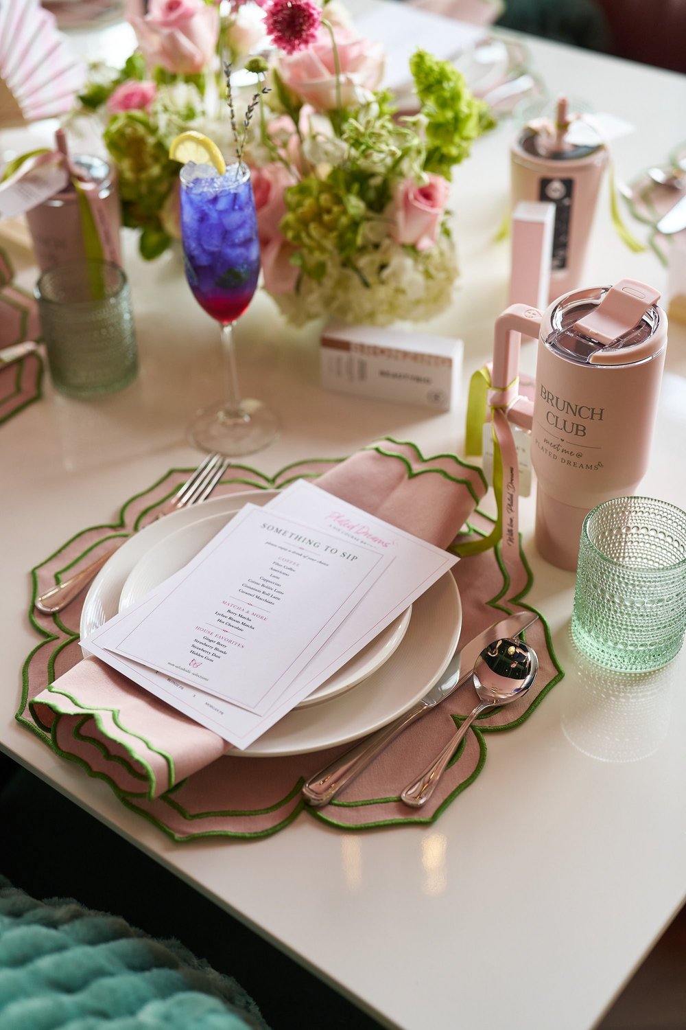 A place setting with a printed menu, pink napkin and Brunch Club tumbler
